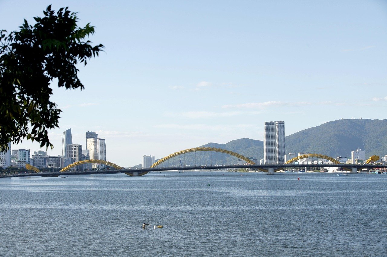 Schilderachtig uitzicht op de Dragon Bridge over de Han River met de skyline van de stad en bergen in Da Nang, Vietnam onder een heldere blauwe lucht