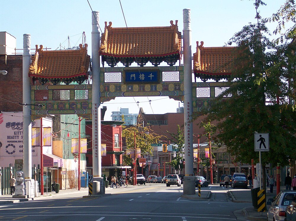 Chinese Poort in Chinatown Wijk Traditionele Chinese poort in een drukke stedelijke Chinatown wijk met auto's en voetgangers op straat