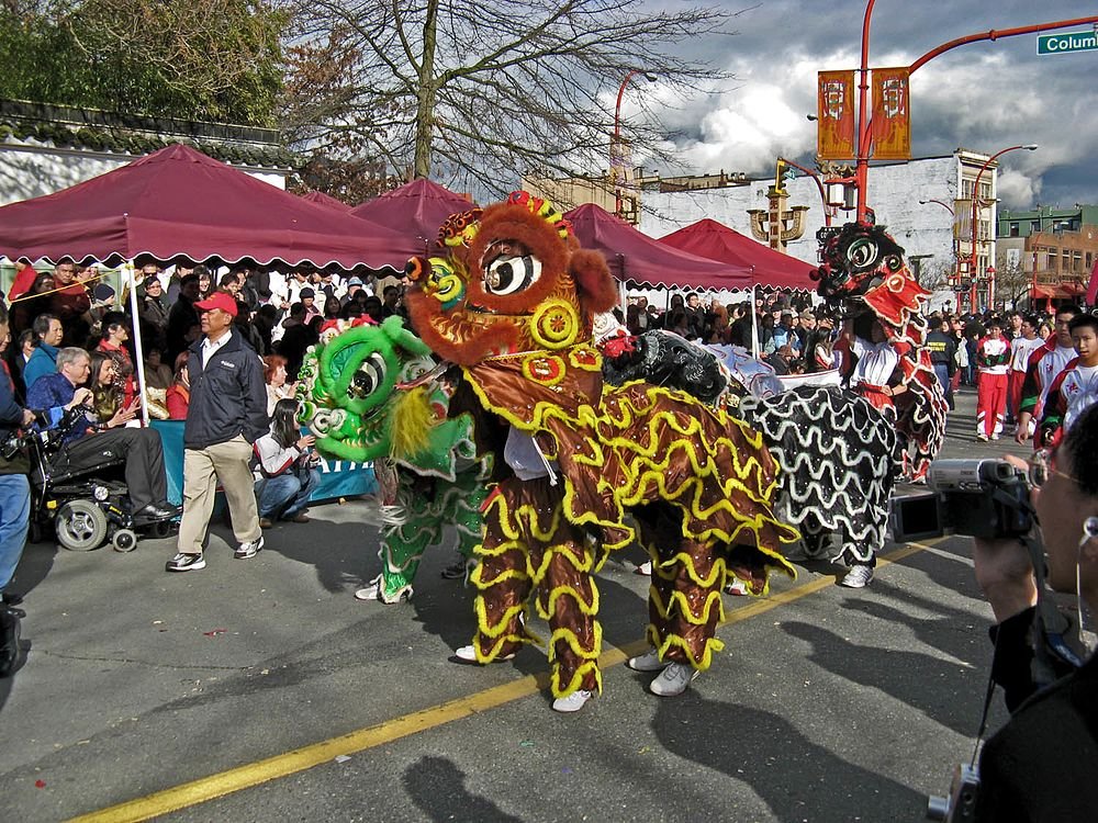 Chinese leeuwendans op buiten cultureel festival Kleurrijke traditionele Chinese leeuwendansvoorstelling op een buitenfestival met menigte en tenten op de achtergrond
