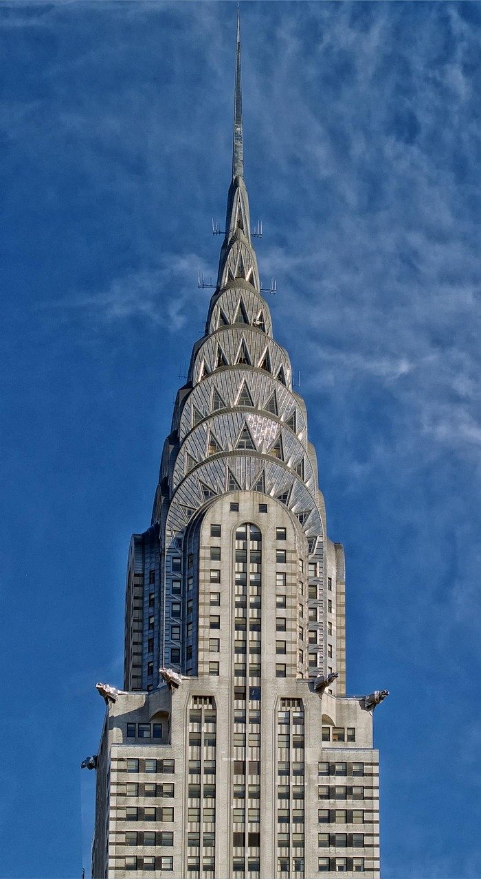 Close-up van de iconische Chrysler Building-spits met zijn Art Deco-architectuur tegen een blauwe lucht