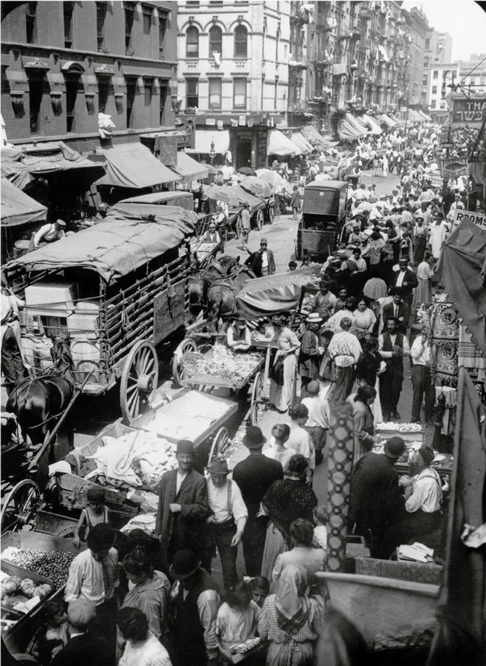 Drukke historische straatmarkt met door paarden getrokken karren Historische zwart-wit foto van een drukke straatmarkt met door paarden getrokken karren en veel mensen die winkelen