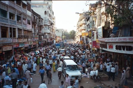 Drukke Indiase straatmarkt met menigten en voertuigen Drukke drukke straatmarkt in een Indiase stad met talrijke voetgangers, voertuigen en winkels aan beide zijden tijdens de dag
