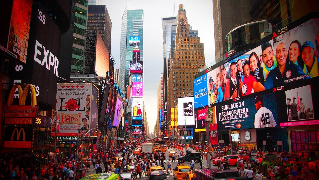 Druk Times Square in New York City met menigten, gele taxi's en levendige digitale billboards die merken en evenementen adverteren