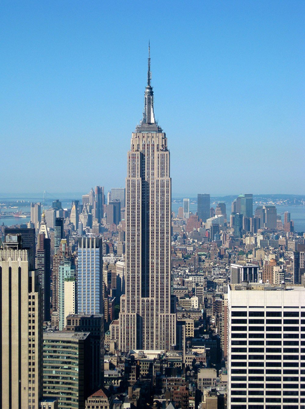 Empire State Building in de skyline van New York City Empire State Building torent boven de skyline van New York City uit op een heldere zonnige dag met blauwe lucht op de achtergrond