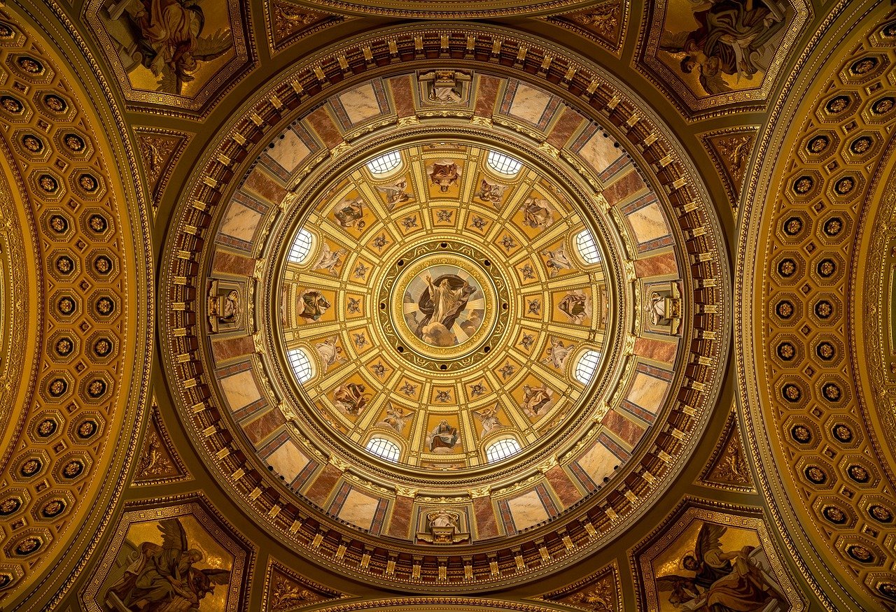 Ingewikkeld versierde gouden koepelplafond met religieuze fresco's en sierlijke architectonische details in een historisch gebouw