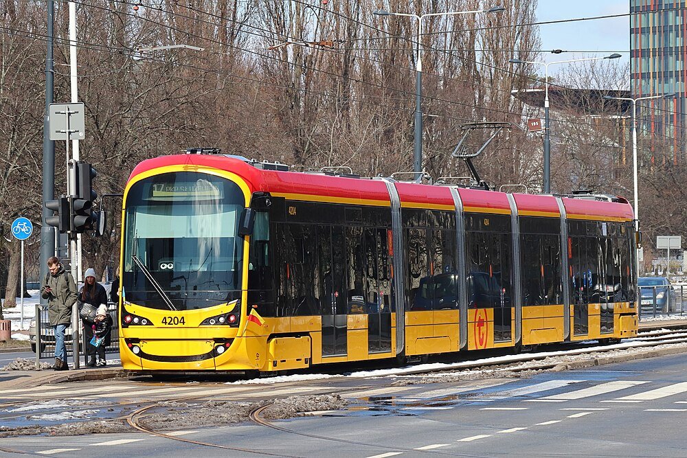 Moderne gele en rode tram 4204 op stadsstraat met passagiers die wachten bij tramhalte in de winter