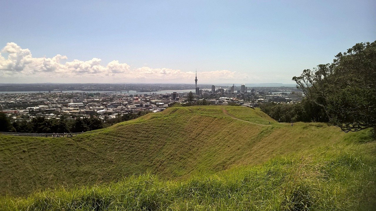 Een panoramisch uitzicht op de skyline van Auckland met de Sky Tower vanuit een grasrijke vulkanische krater op een heldere zonnige dag