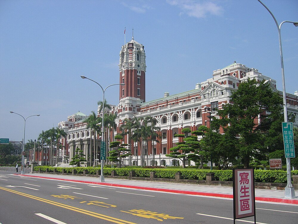 Historisch overheidsgebouw met klokkentoren in Taipei Historisch rood en wit overheidsgebouw met klokkentoren en palmbomen langs een brede straat in Taipei, Taiwan