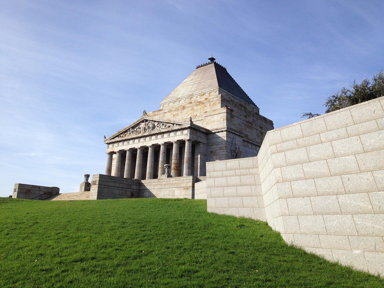Shrine of Remembrance oorlogsmonument met klassieke architectuur en groen gazon onder heldere blauwe lucht