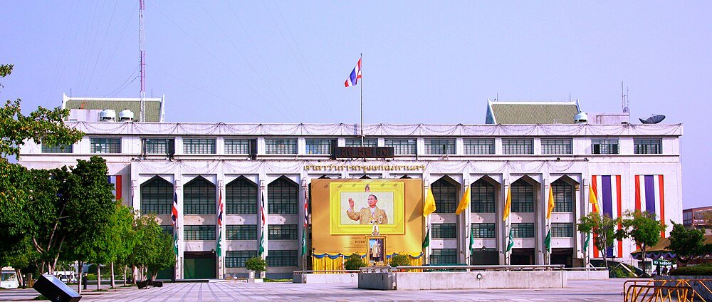 Thais regeringsgebouw met portret van de koning en vlaggen Regeringsgebouw in Thailand met groot portret van de Thaise koning en nationale vlaggen prominent weergegeven