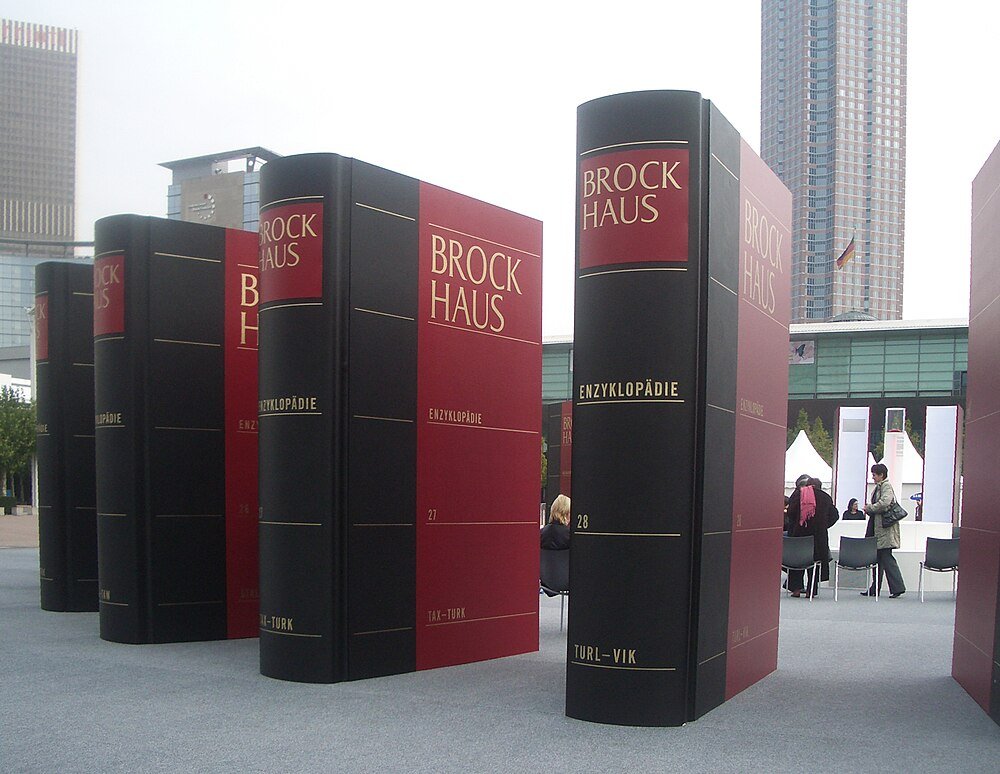 Grote Brockhaus encyclopedie boeksculpturen buiten Grote Brockhaus encyclopedie boeksculpturen tentoongesteld in een stedelijke omgeving met mensen in de buurt