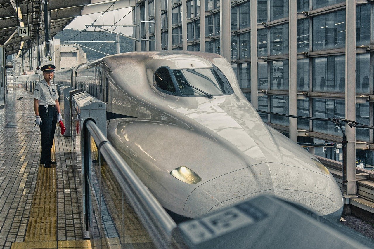 Moderne Japanse Shinkansen-bullet train op perron met uniform personeel in druk station