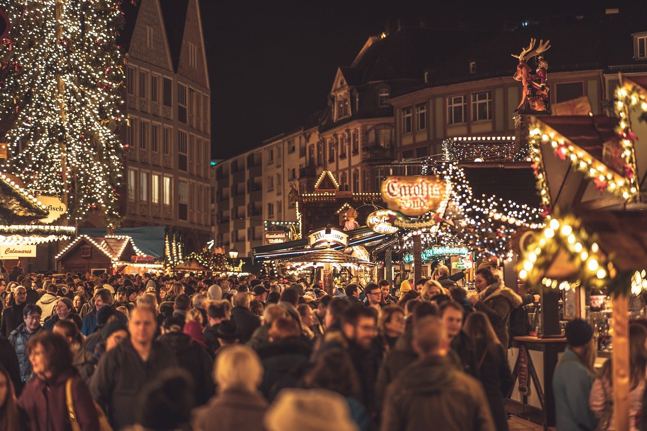 Drukke kerstmarkt 's nachts met feestelijke lichtjes, versierde kraampjes en mensen die genieten van kerstinkopen en vieringen