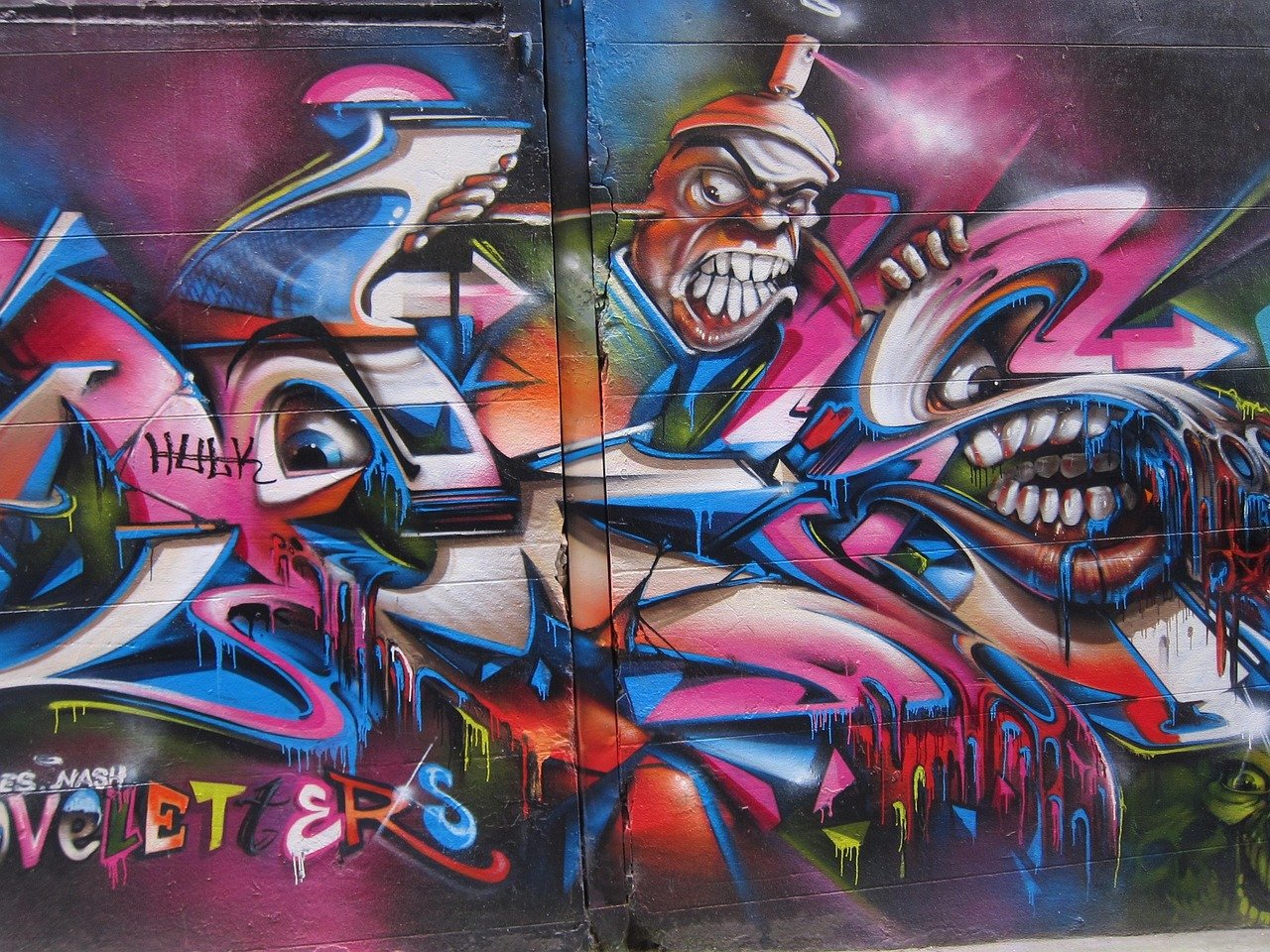 Kleurrijke graffiti kunst op muur met abstracte gezichten met overdreven tanden en levendige druipende verf effecten