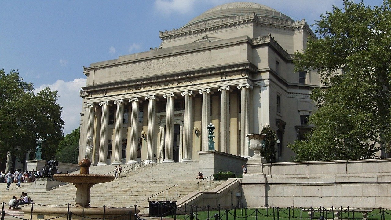 Het iconische bibliotheekgebouw van Columbia University met grote zuilen en trappen onder een heldere hemel in New York City