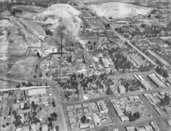 Luchtfoto van industriële stad met fabrieken en huizen Luchtfoto zwart-wit van een industriële stad met fabrieken, woonhuizen en omliggende heuvels.