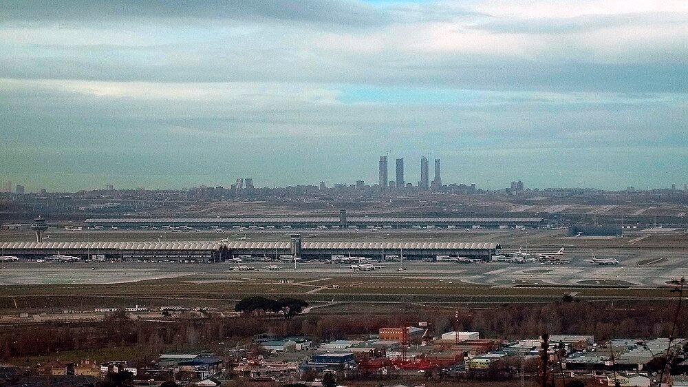 Luchtfoto van internationale luchthaven met vliegtuigen Luchtfoto van een grote internationale luchthaven met meerdere vliegtuigen en terminalgebouwen onder een bewolkte hemel