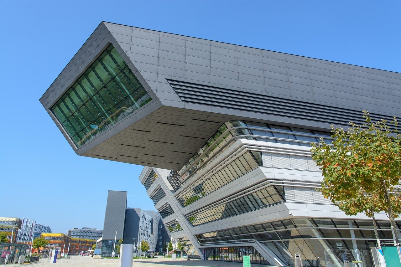 Modern futuristisch universiteitsgebouw met hoekig ontwerp en grote glazen ramen onder een heldere blauwe lucht