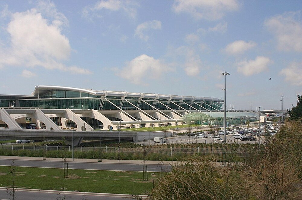 Moderne luchthaven terminal met parkeerplaats Modern luchthaven terminalgebouw met glazen gevel, parkeerplaats en heldere blauwe lucht op een zonnige dag