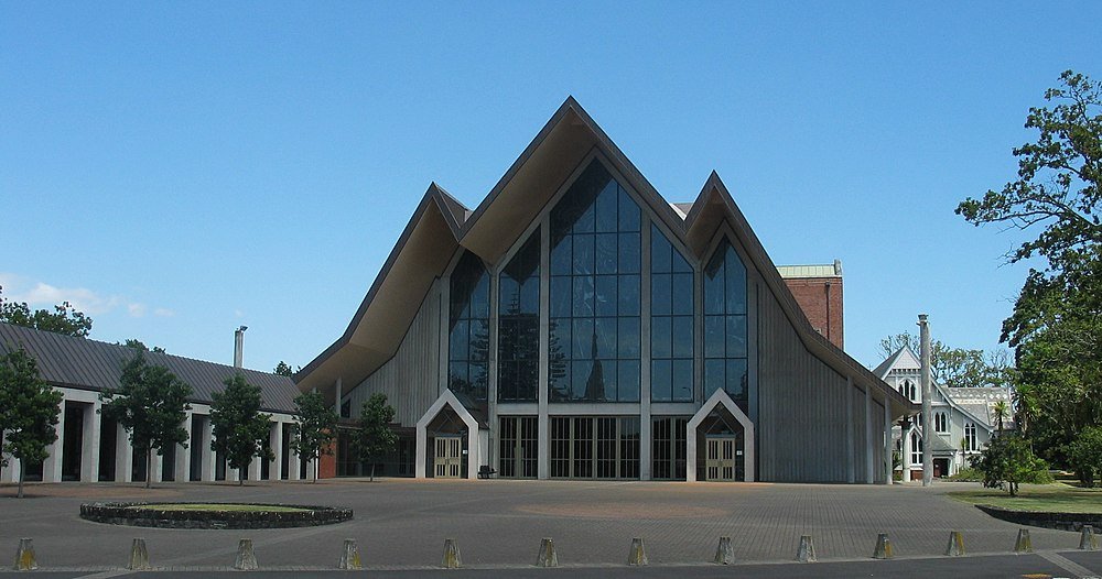 Moderne kerk met hoekig dak en glazen gevel Modern kerkgebouw met grote glazen ramen en uniek hoekig dakontwerp onder een heldere blauwe lucht