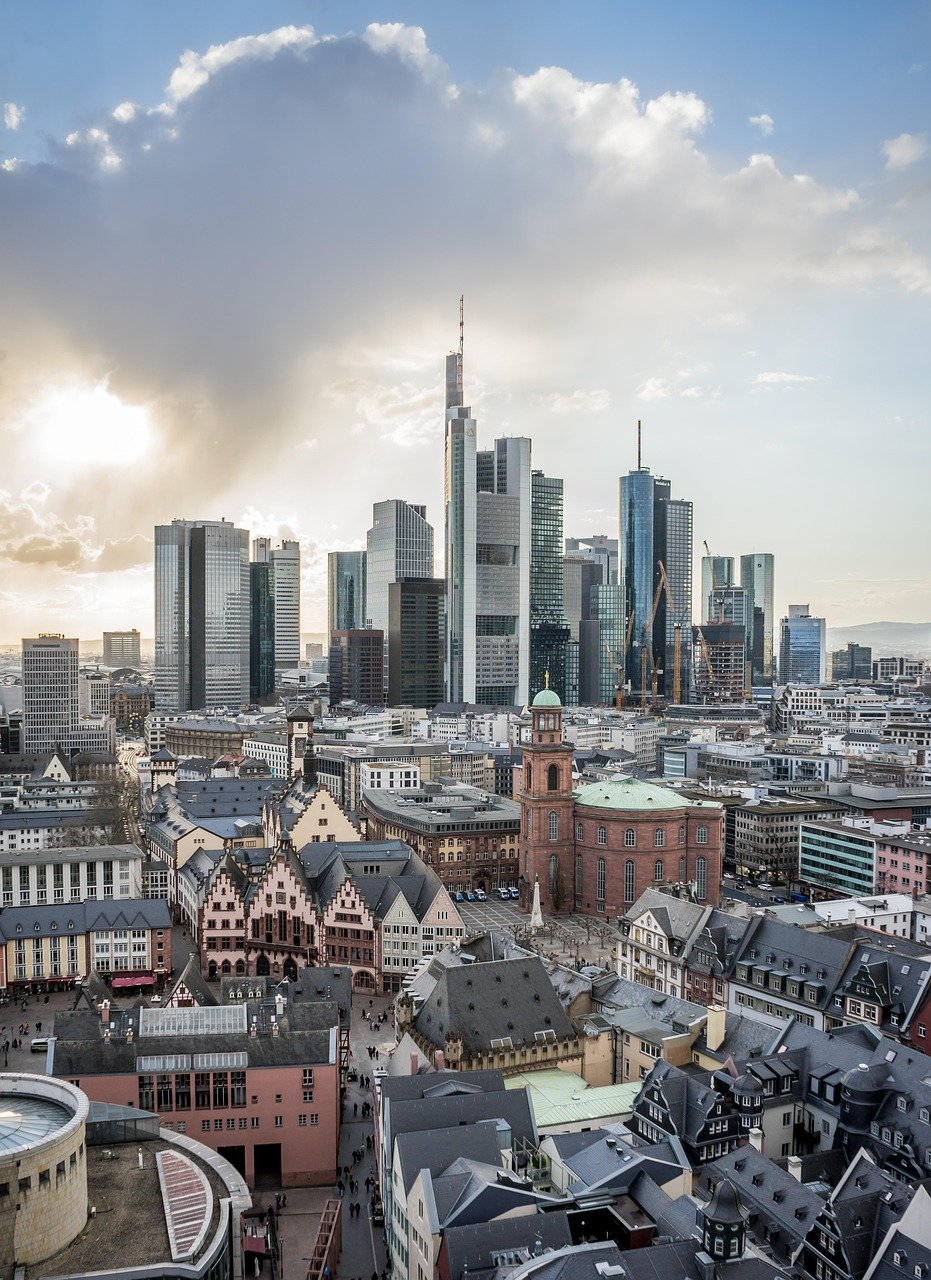Skyline van Frankfurt am Main met moderne wolkenkrabbers en historische gebouwen onder een bewolkte hemel bij zonsondergang