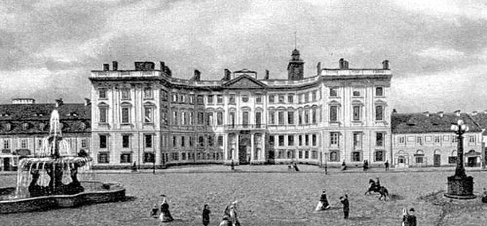 Historisch Europees paleis met fontein en mensen Historische zwart-wit foto van een groot Europees paleis met een fontein en mensen in kleding uit die tijd op het plein