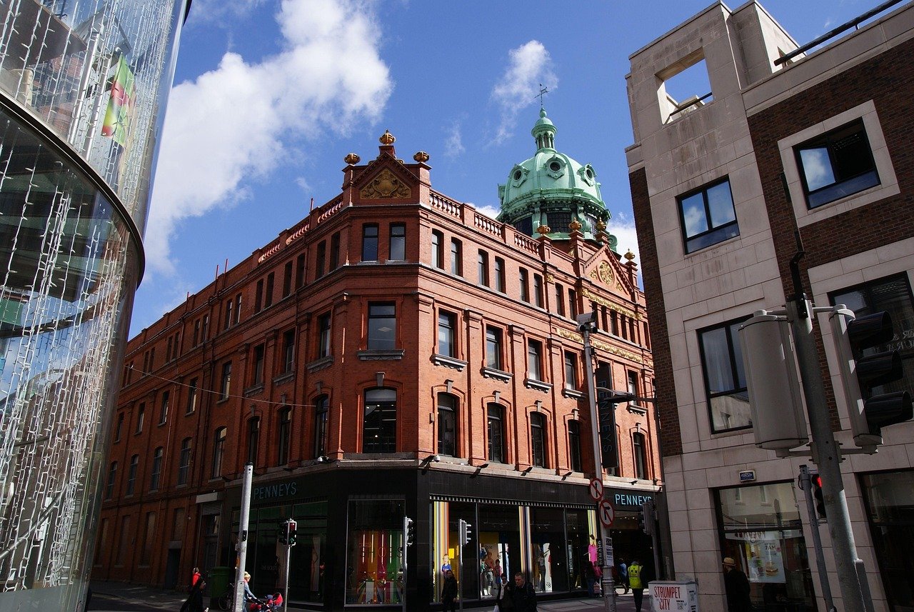 Historisch rood bakstenen gebouw met groene koepel en Penneys winkel op een zonnige dag in een drukke stadsstraat