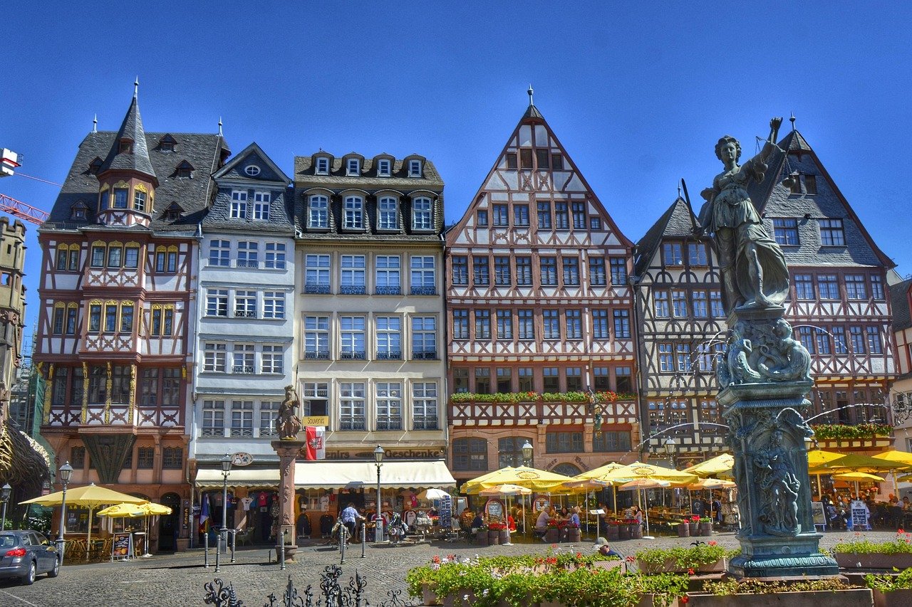 Historische vakwerkhuizen en buitencafés met gele parasols op een Europees stadsplein op een zonnige dag