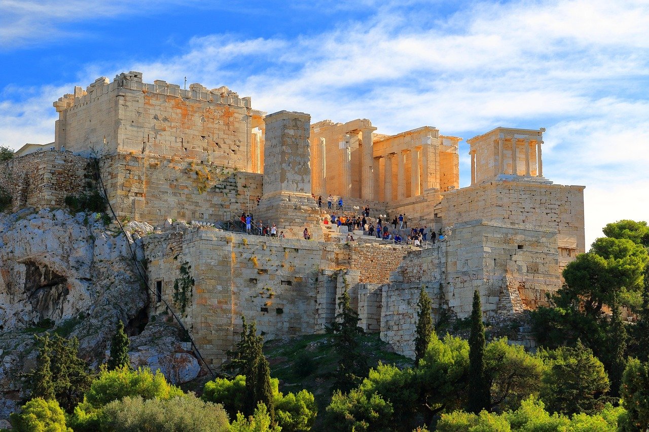 Oude Akropolis van Athene met historische stenen structuren en toeristen onder een heldere blauwe lucht