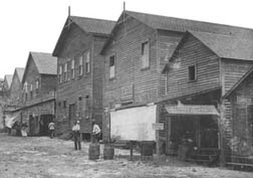 Houten Industriële Pakhuizen Begin 20e Eeuw Historische zwart-wit foto van oude houten industriële pakhuizen met arbeiders buiten in het begin van de 20e eeuw