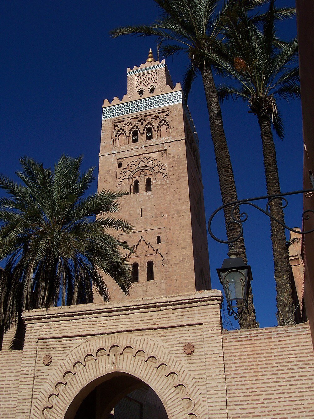 Historische moskeetorens met palmbomen in Marrakech Hoge historische moskeetorens met ingewikkelde steenhouwkunst en palmbomen onder een heldere blauwe hemel in Marrakech Marokko