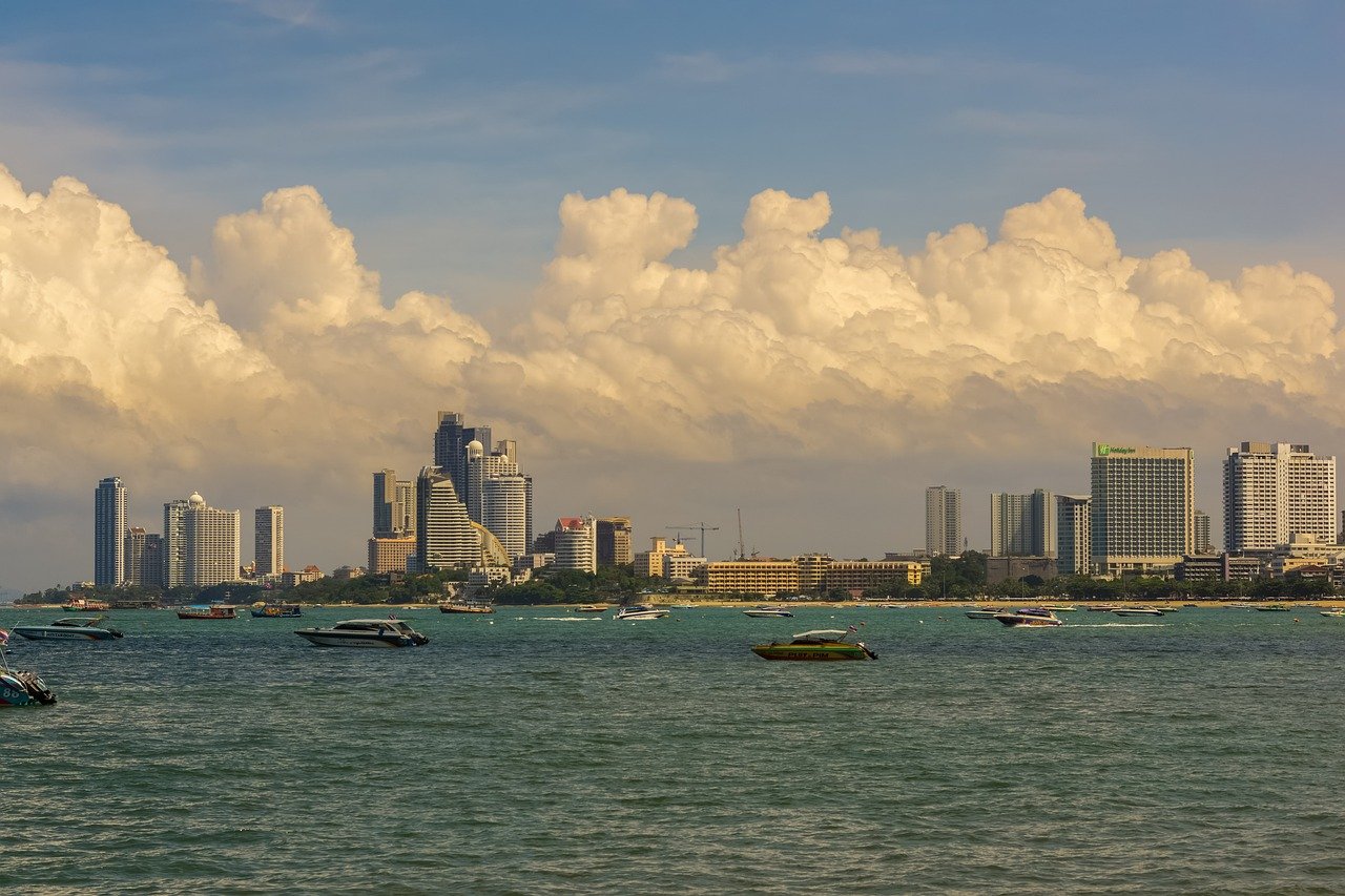 Stadssilhouet met hoogbouw en boten op het water onder een bewolkte hemel overdag