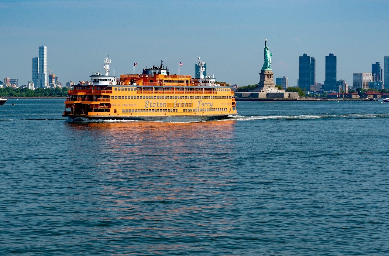 Staten Island Ferry varend in de haven van New York met het Vrijheidsbeeld en de skyline van de stad op de achtergrond op een heldere dag