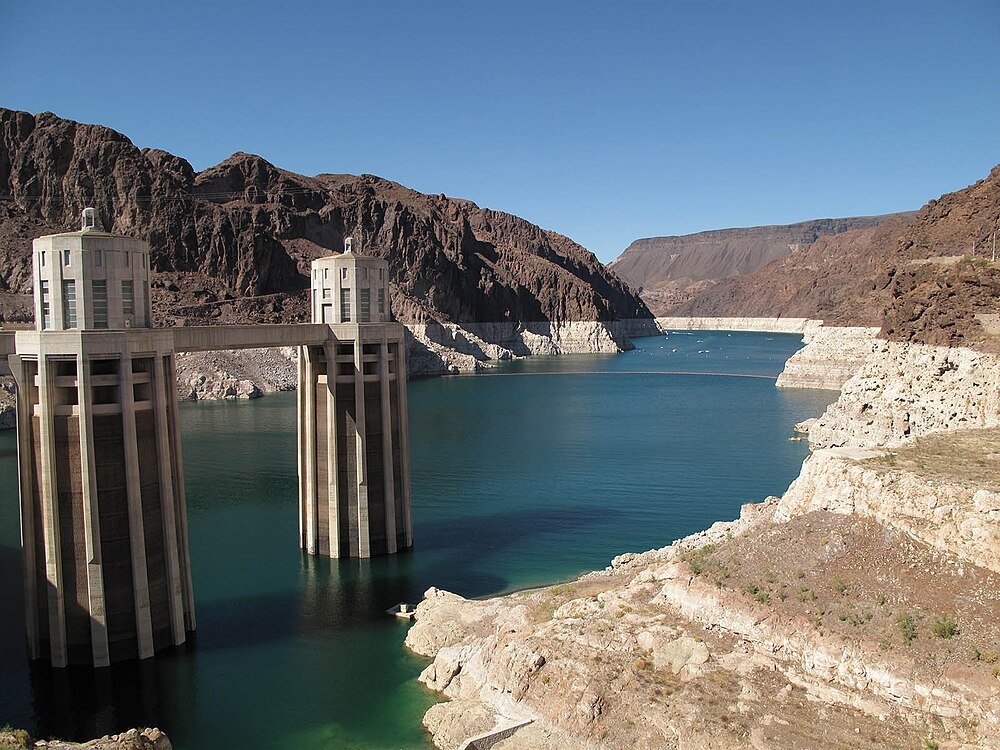 Inlaattorens van de Hoover Dam en uitzicht op het reservoir Inlaattorens van de Hoover Dam met waterreservoir en rotsachtig woestijnlandschap onder een heldere blauwe lucht