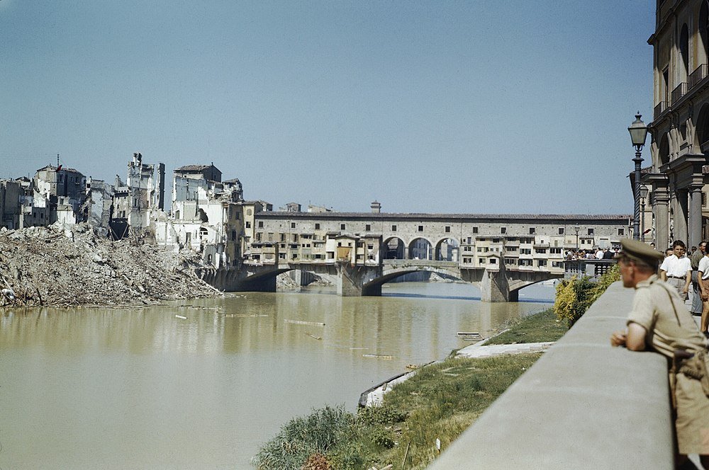 Ponte Vecchio Brug en Oorlogs-beschadigde Gebouwen Florence Historische Ponte Vecchio-brug over de Arno-rivier met beschadigde gebouwen en puin op de oever in Florence, Italië