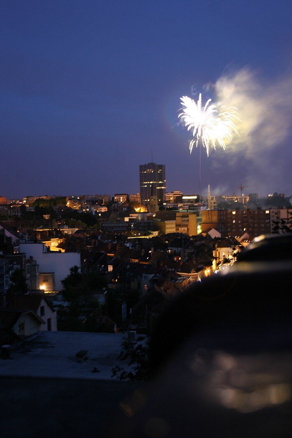 Vuurwerk boven de stadsskyline 's nachts Nachtelijke stadsgezicht met verlichte gebouwen en heldere vuurwerkexplosies in de lucht boven stedelijk gebied