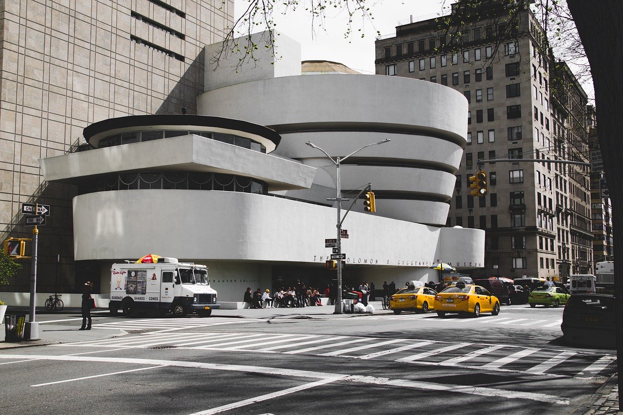Buitenaanzicht van het Solomon R. Guggenheim Museum in New York City met gele taxi's en een ijscowagen in de buurt