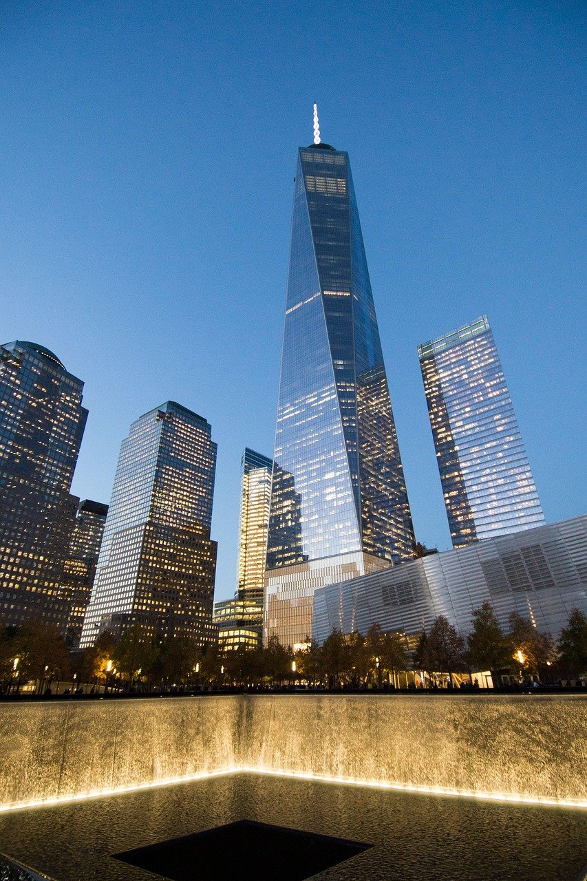 One World Trade Center en 9/11 Memorial weerspiegeld in water bij schemering in de skyline van New York City