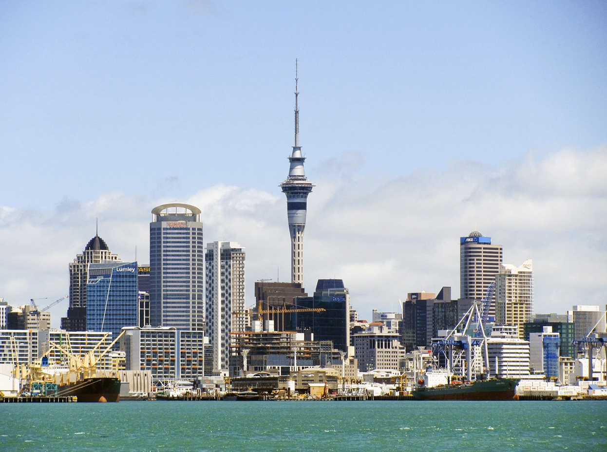 Skyline van Auckland met Sky Tower en waterkant Skyline van de stad Auckland met de Sky Tower, waterkant en vrachtschepen onder een heldere blauwe lucht in Nieuw-Zeeland