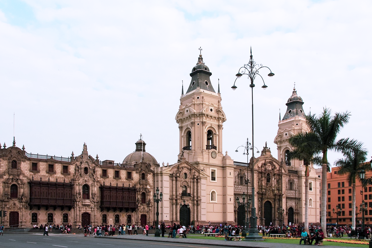 Lima Plaza Mayor Kathedraal en Regeringspaleis Historische koloniale kathedraal en regeringspaleis op het Plaza Mayor van Lima met toeristen en palmbomen onder een bewolkte hemel