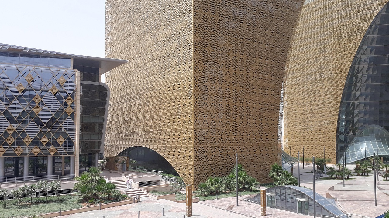 Moderne kantoorgebouwen met gouden traliewerkgevel Moderne kantoorgebouwen met unieke gouden traliewerkgevel en glazen structuren in een aangelegd stedelijk gebied onder een heldere hemel