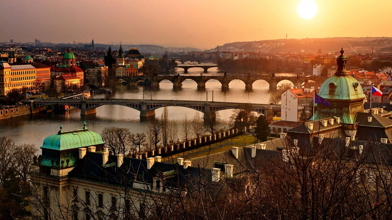 Schilderachtig uitzicht op de stad Praag met de Vltava-rivier en historische bruggen bij zonsondergang, met iconische architectuur en warme verlichting