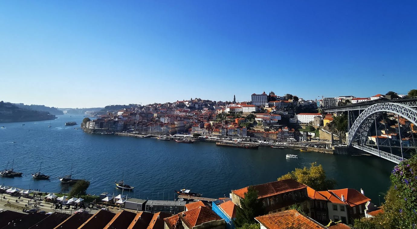 Stadsgezicht van Porto met de Douro-rivier en de Dom Luís I-brug Schilderachtig uitzicht op de stad Porto met de Douro-rivier, historische gebouwen en de Dom Luís I-brug onder een heldere blauwe lucht