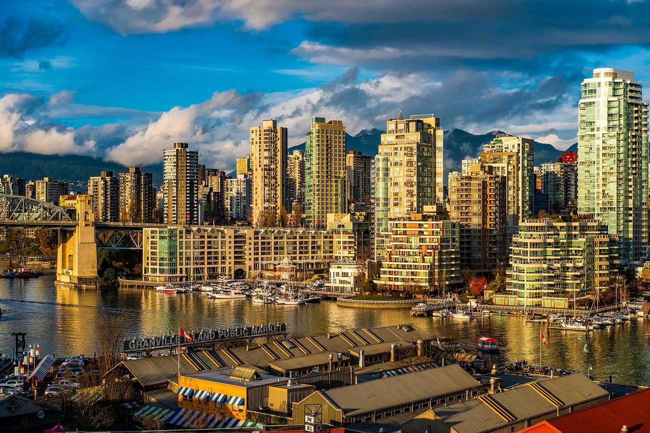 Granville Island Public Market en Vancouver Waterfront Granville Island Public Market met hoogbouw aan het water en boten in de stadsgezicht van Vancouver onder blauwe lucht