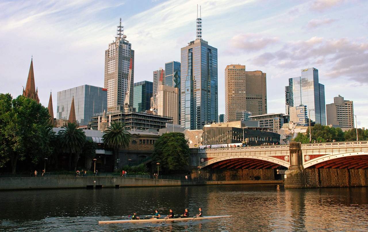 Melbourne skyline met Yarra River en roeiers Melbourne stadsgezicht met Yarra River, moderne wolkenkrabbers, historische gebouwen en een roeiploeg op het water bij zonsondergang
