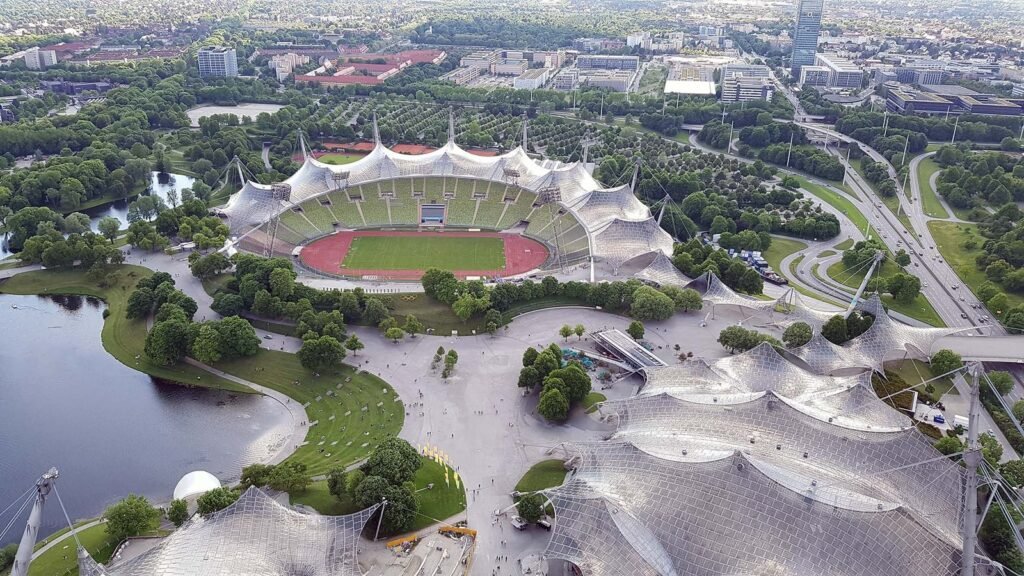 Luchtfoto van het Olympiapark en het Olympiastadion van München met tentdak en de Olympiaturm op de achtergrond