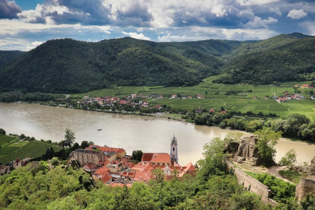 Luchtfoto van Dürnstein aan de Donau in de Wachau, met wijngaarden en een blauwe barokke kerktoren, een dagtrip vanuit Wenen